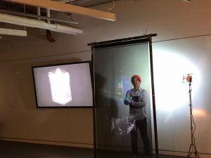 A student stands in front of a horizontal glass screen.